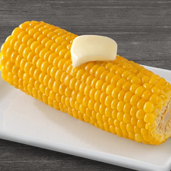 Golden corn on the cob with a pat of melting butter, served on a white plate.