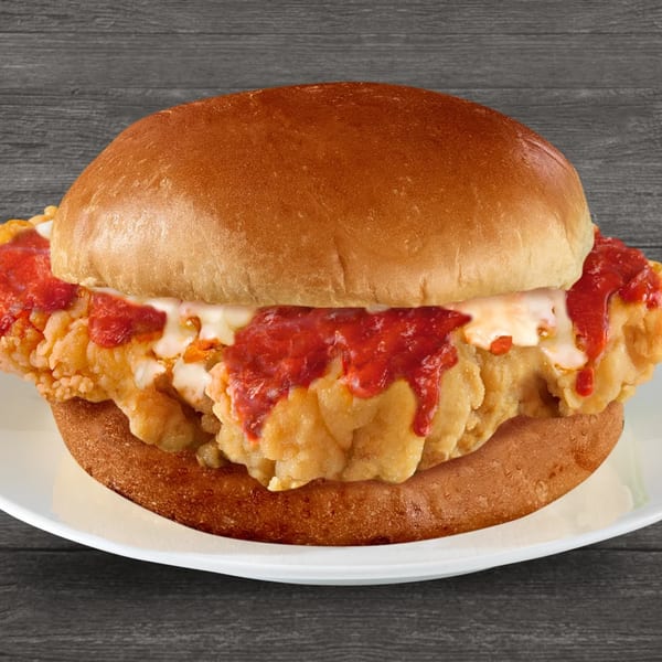 Brown's Chicken fried chicken sandwich with red sauce and melted cheese on a white plate.