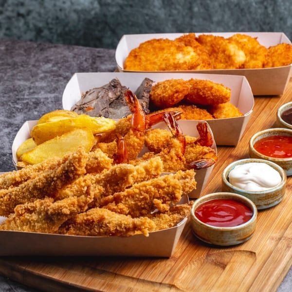 Brown's Chicken fried chicken, shrimp, potato wedges, and nuggets with dipping sauces on a wooden board.